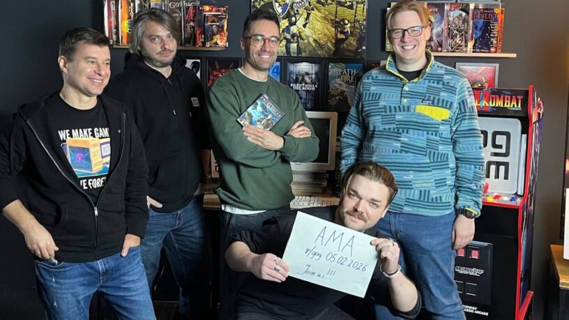 Cinco membros da equipe do GOG posam em uma sala decorada com memorabilia de videogames. Atrás delas há prateleiras cheias de caixas de jogos clássicos, como Gothic, Silent Hill 4: The Room e Breath of Fire. À direita, há uma máquina de arcade de Mortal Kombat. Uma pessoa em pé segura uma caixa de jogo; outra, sentada à frente, segura um cartaz escrito: ‘AMA — r/gog 05.02.2026 — Join us!!!’.